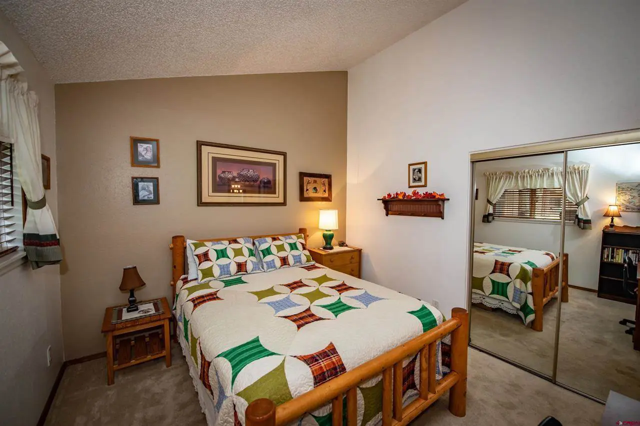 A bedroom with a bed, dresser and mirror.