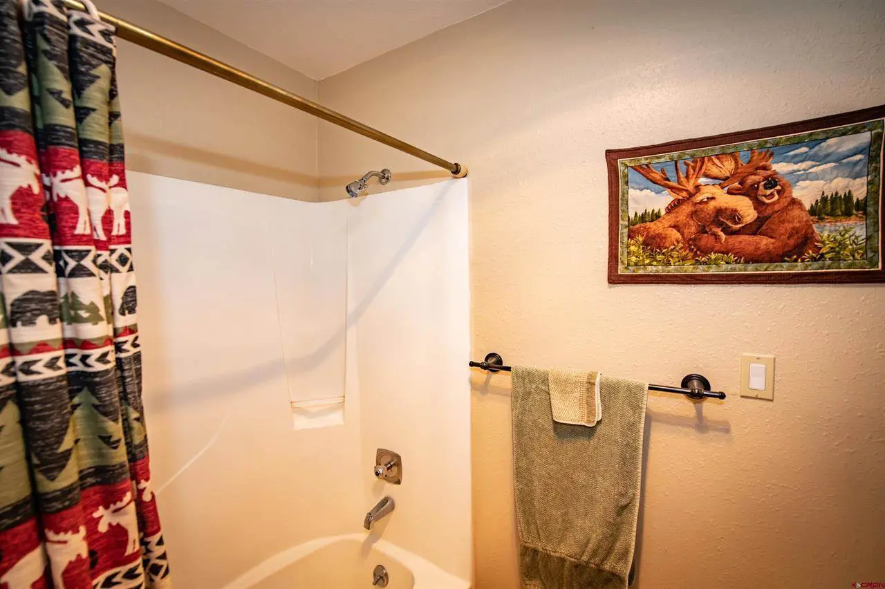 A bathroom with a bear shower curtain.