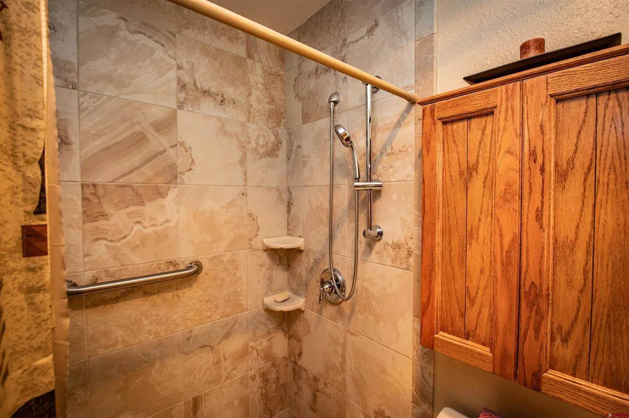 A bathroom with a walk in shower and wooden cabinets.