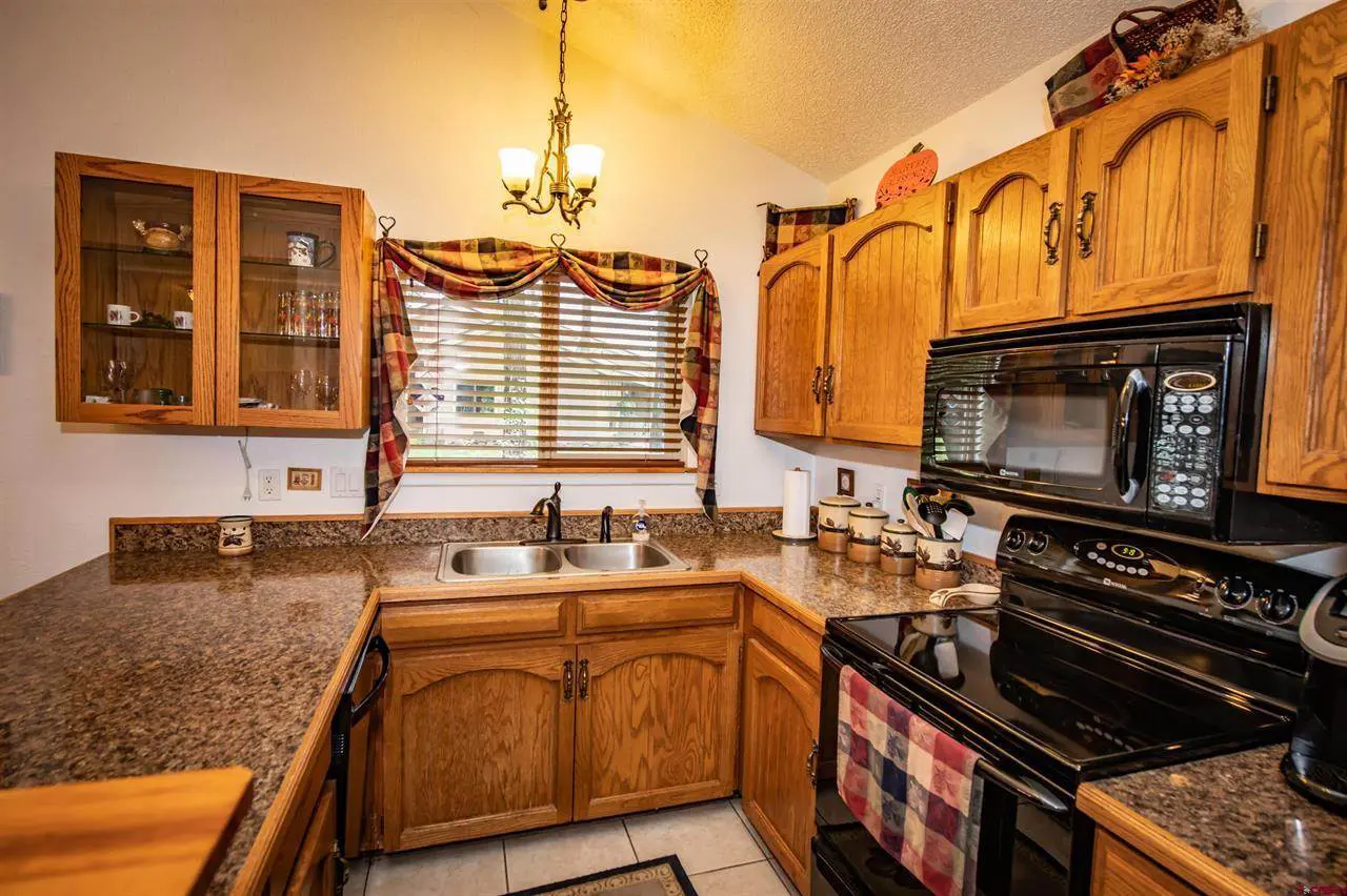 A kitchen with black appliances and granite counter tops.