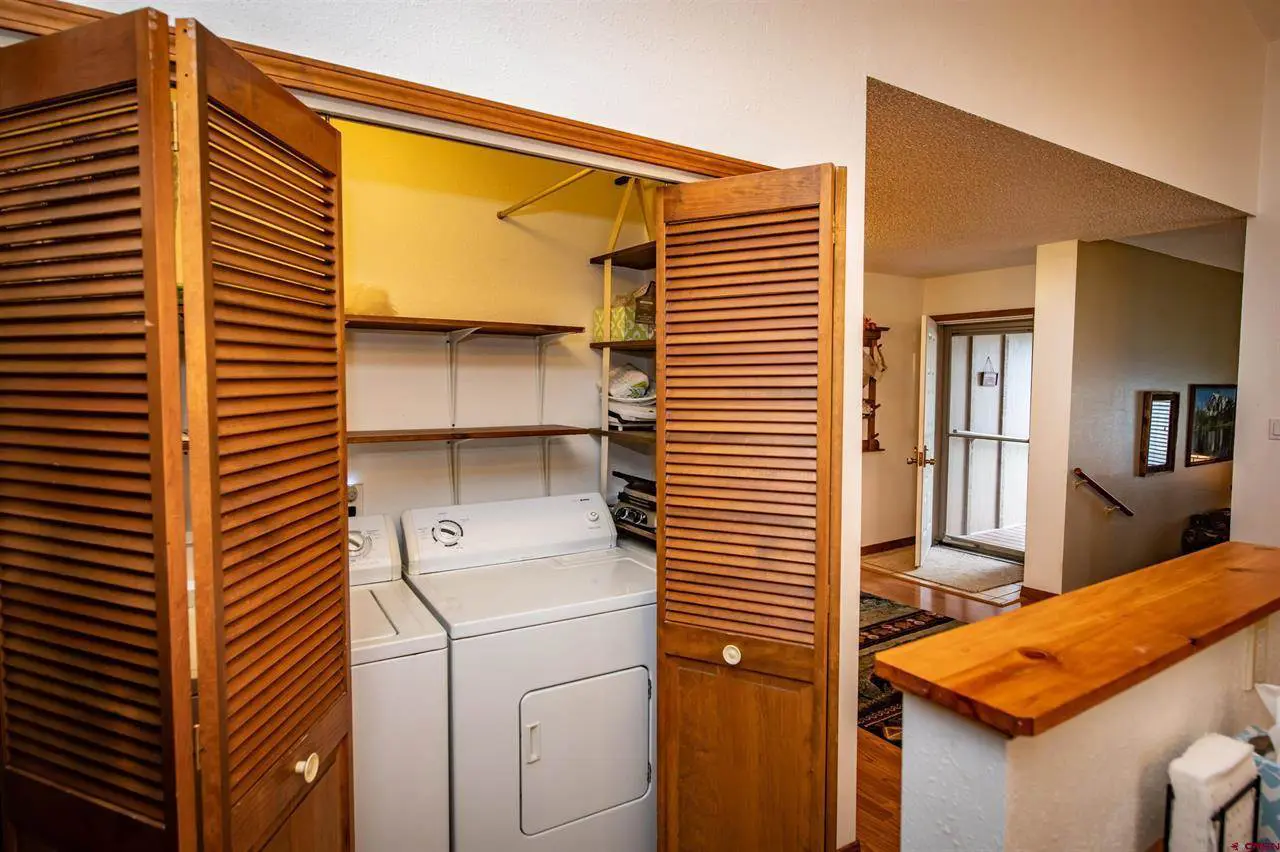 A laundry room with wooden doors and a washer and dryer.