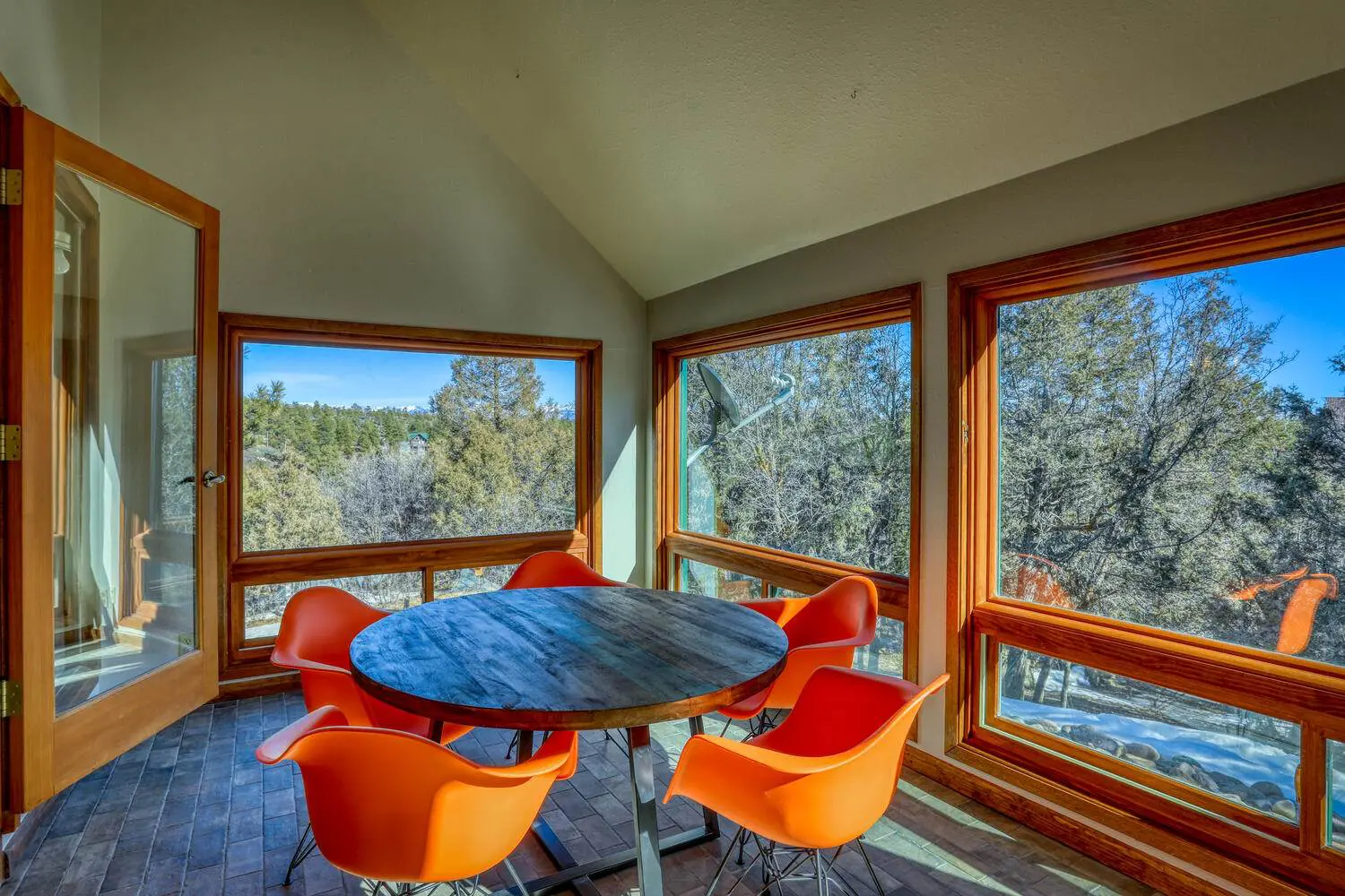 A dining room with orange chairs and a view of the mountains.