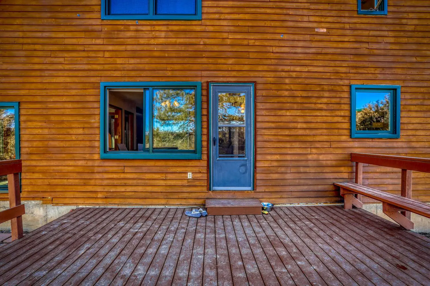 A wooden deck with a bench and a window.