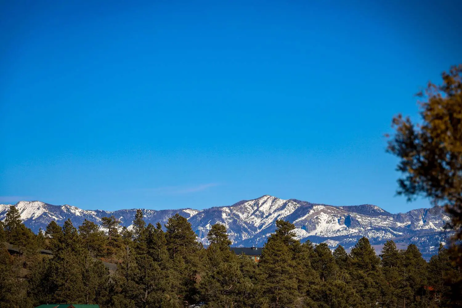 A blue sky with snow capped mountains in the background.