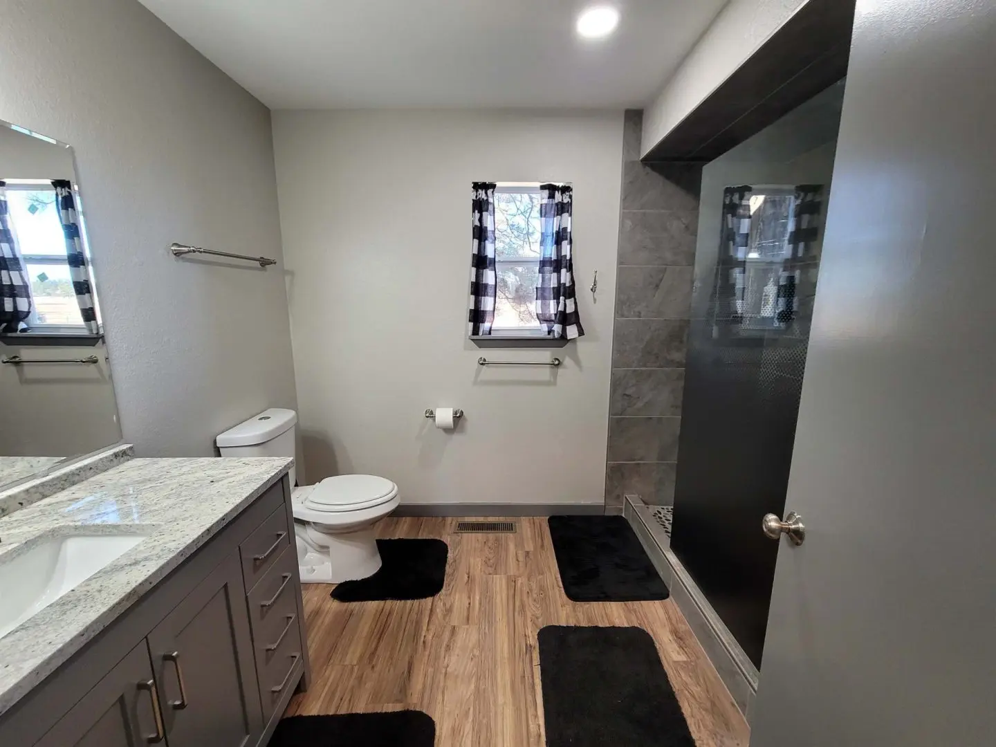 A bathroom with gray tile floors and a shower.