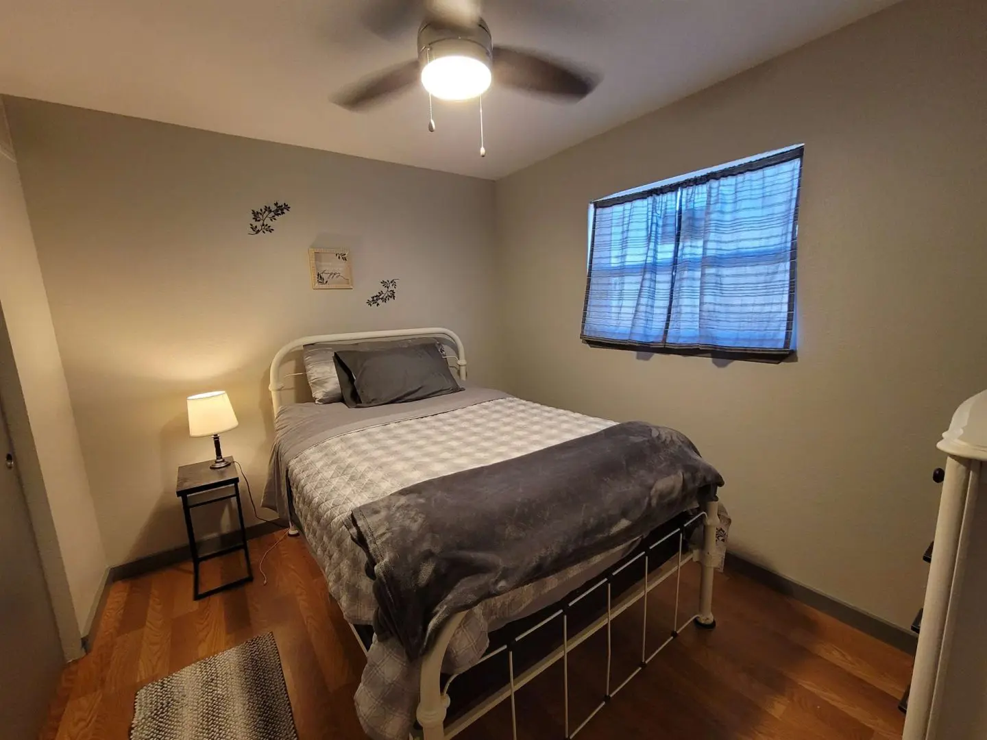 A small bedroom with a bed and a ceiling fan.