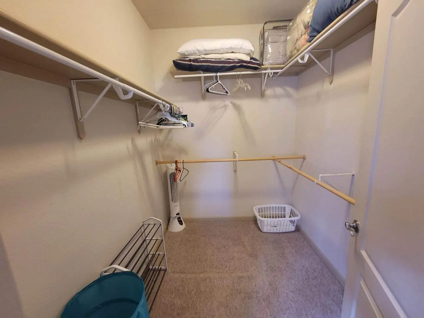 A closet with clothes and towels hanging on the racks.