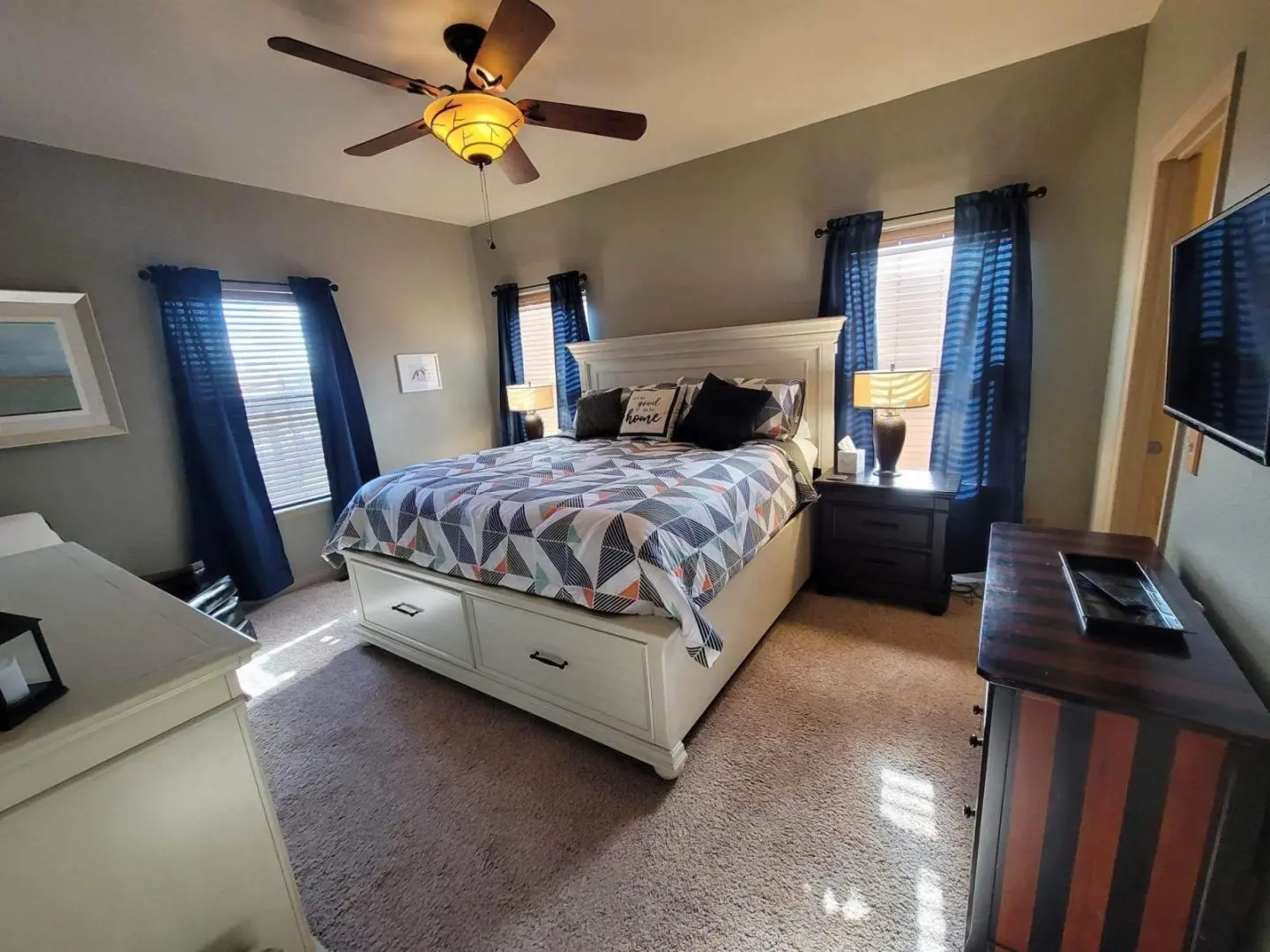 A bedroom with a bed, dresser, and ceiling fan.