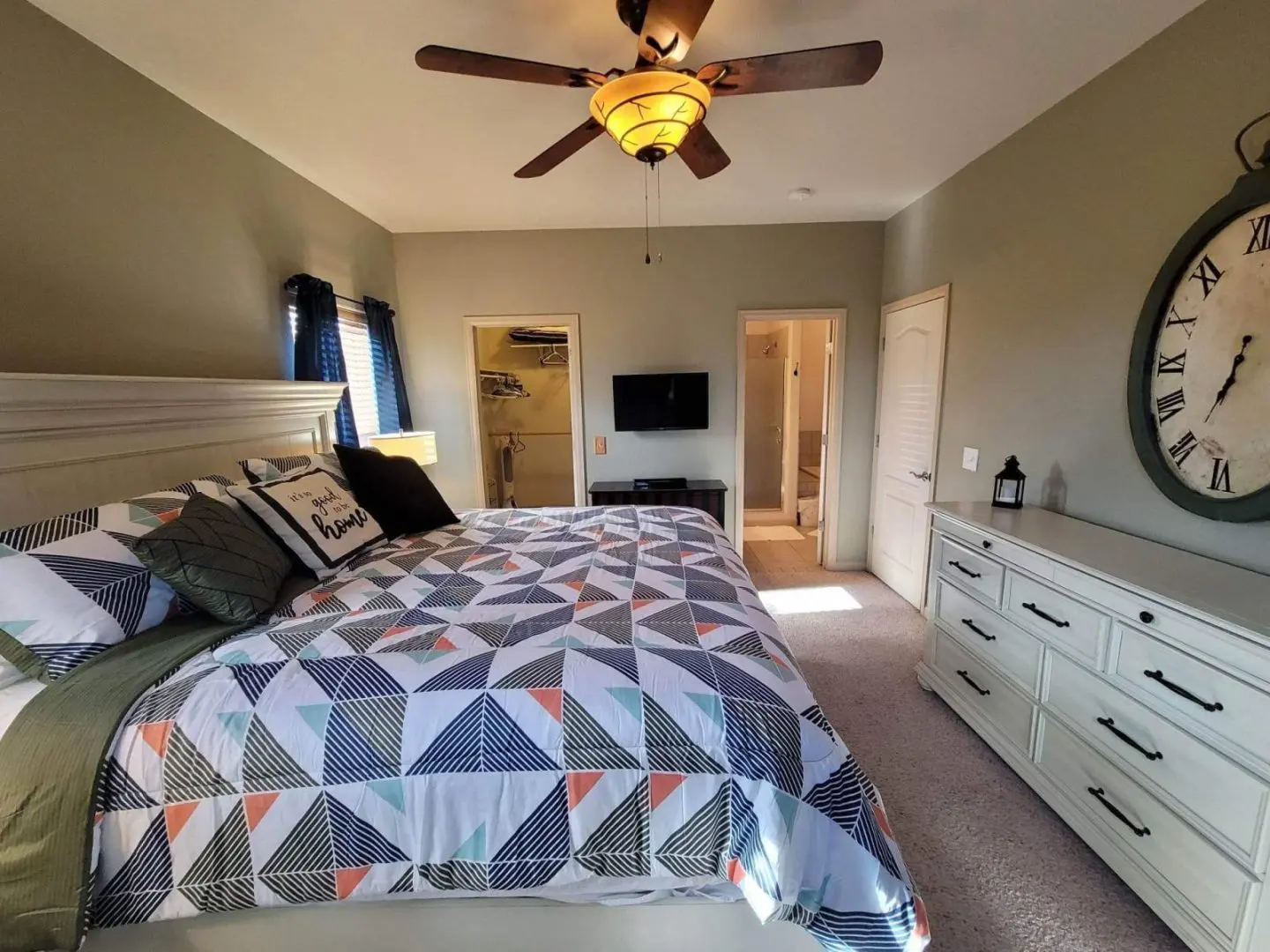 A bedroom with a bed, dresser, and ceiling fan.