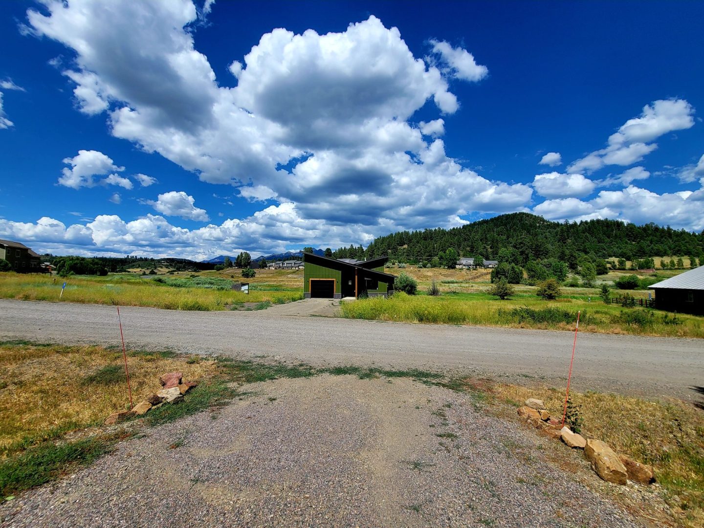 A dirt road leading to a house in the mountains.