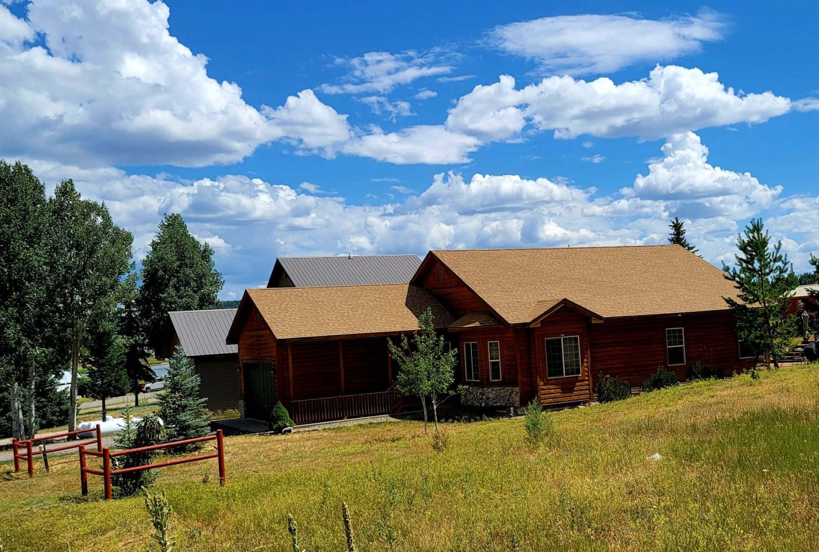 A log cabin on a grassy hillside.