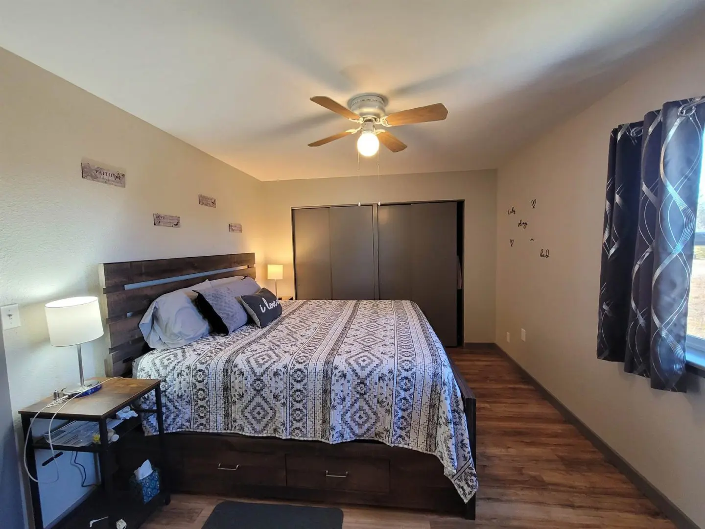 A bedroom with hardwood floors and a ceiling fan.