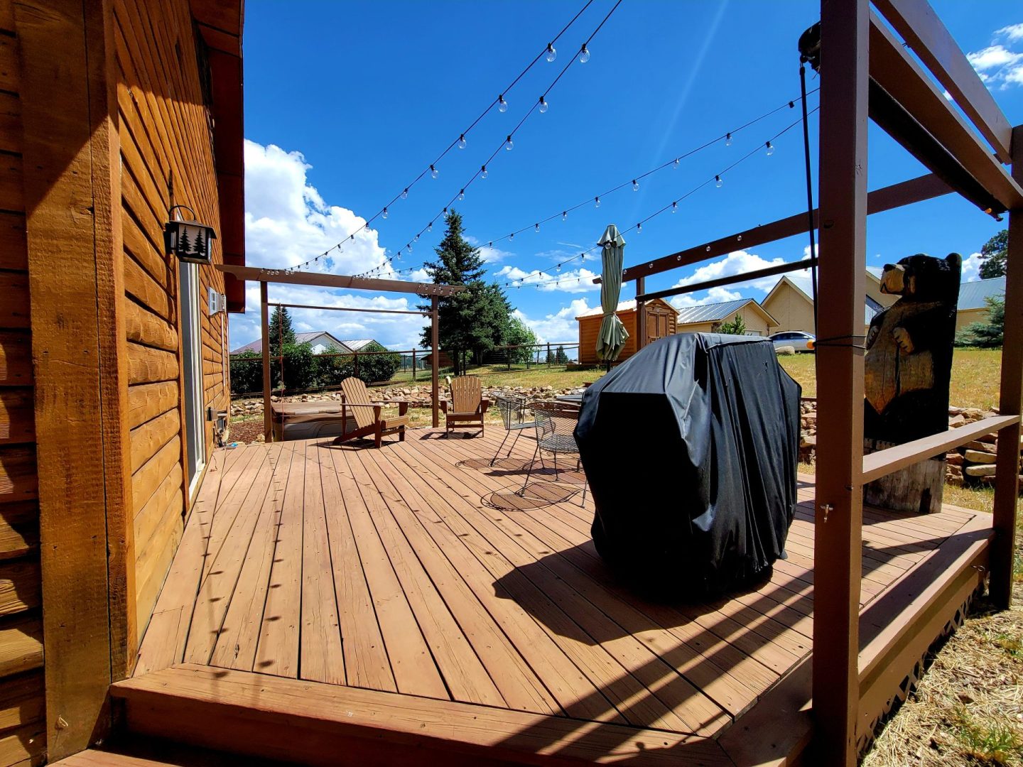 A wooden deck with a grill and lights.