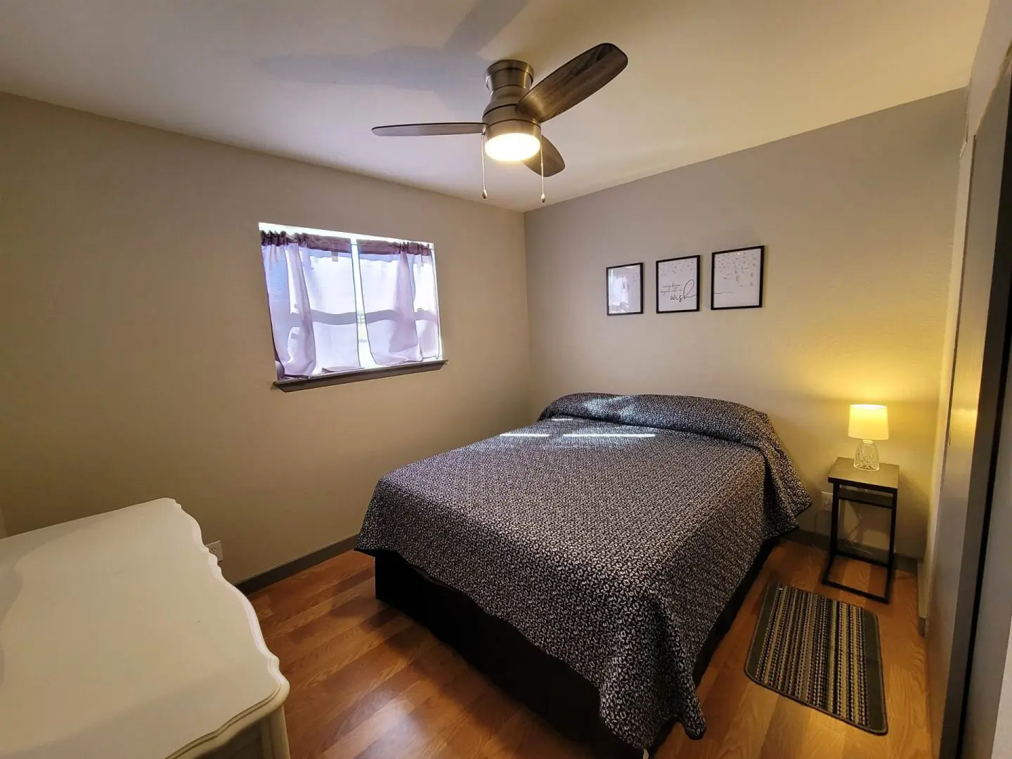 A bedroom with hardwood floors and a ceiling fan.