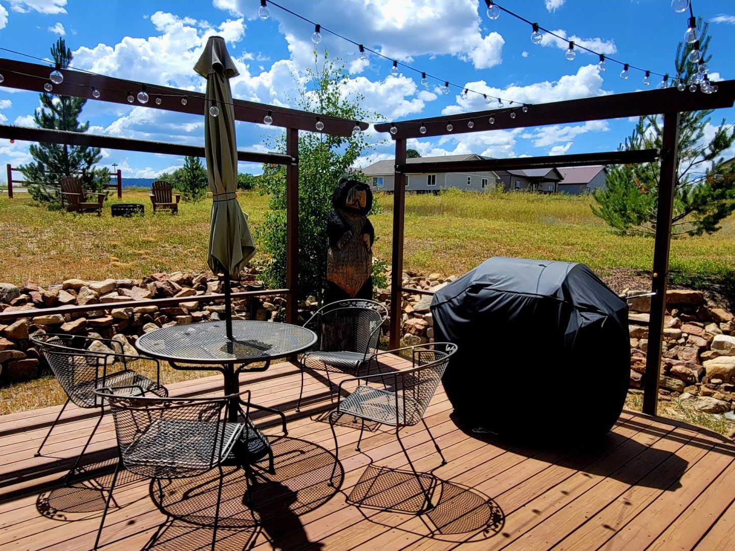 A deck with a table and chairs and a grill.