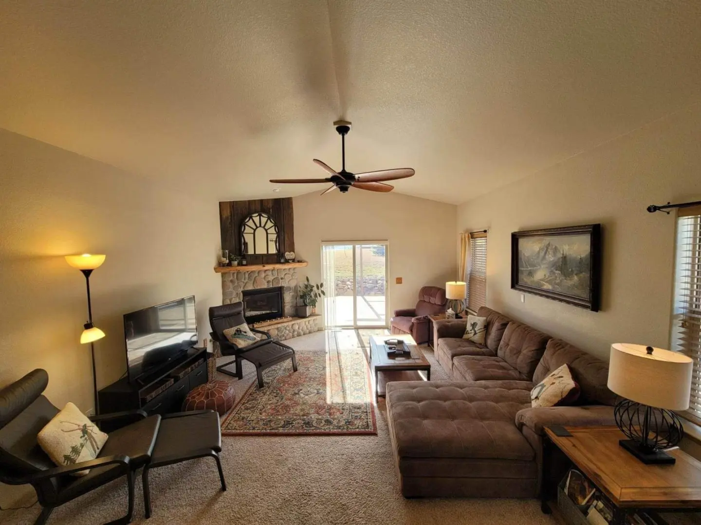 A living room with a fireplace and a ceiling fan.