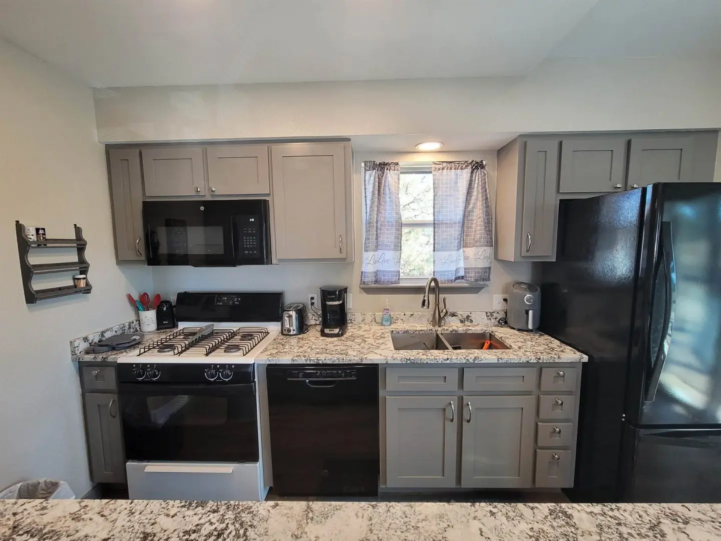 A kitchen with black appliances and granite counter tops.