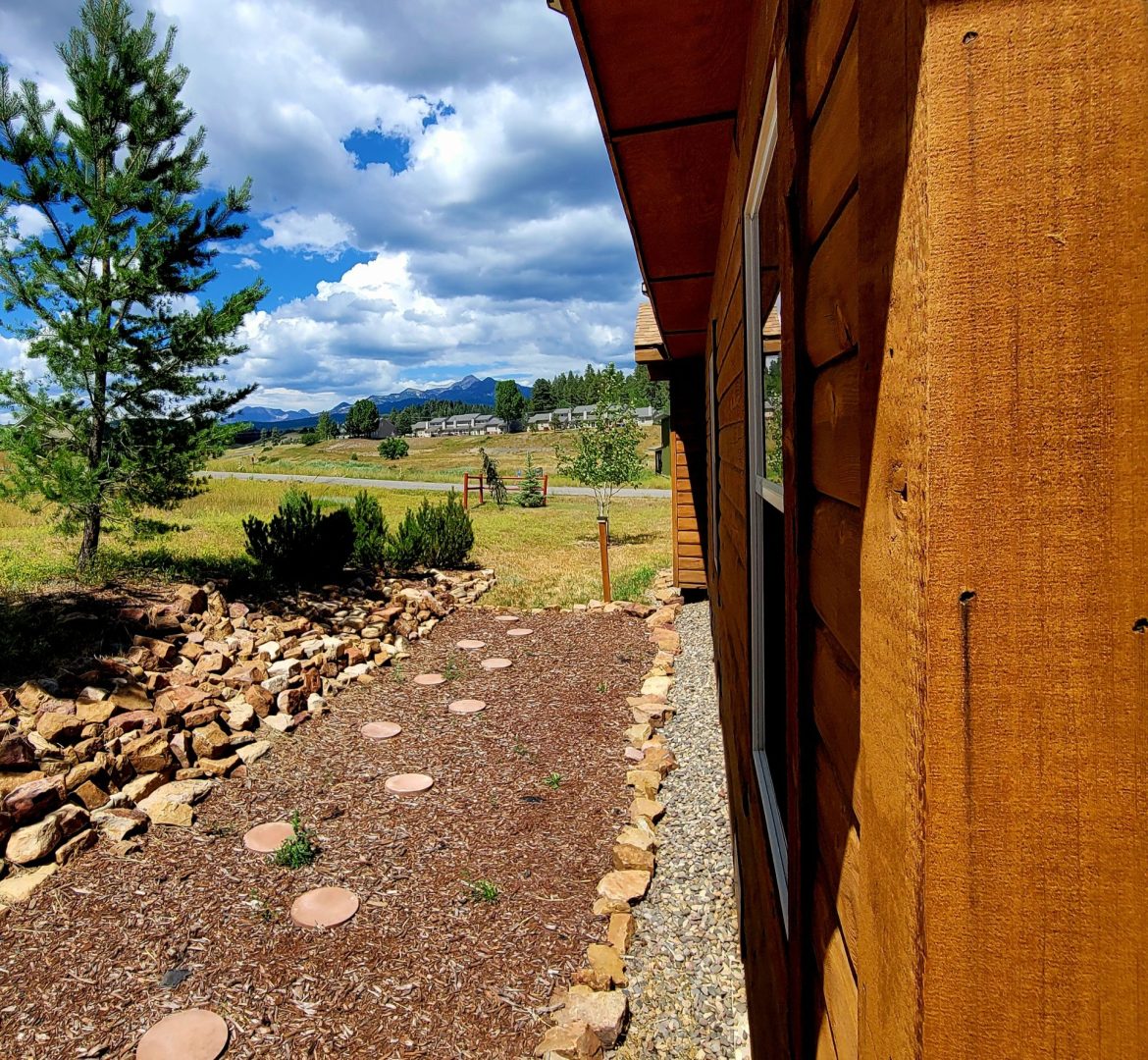 A view of a log cabin with rocks and grass.