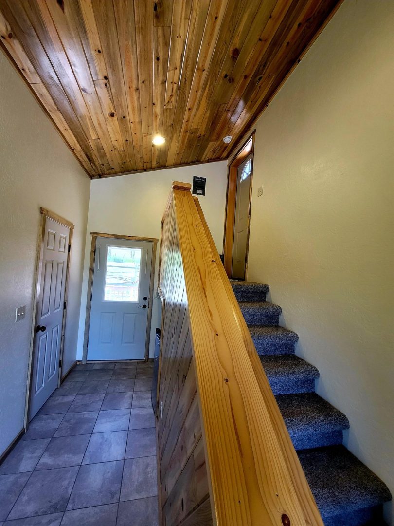 A hallway with a wooden ceiling and wooden stairs.