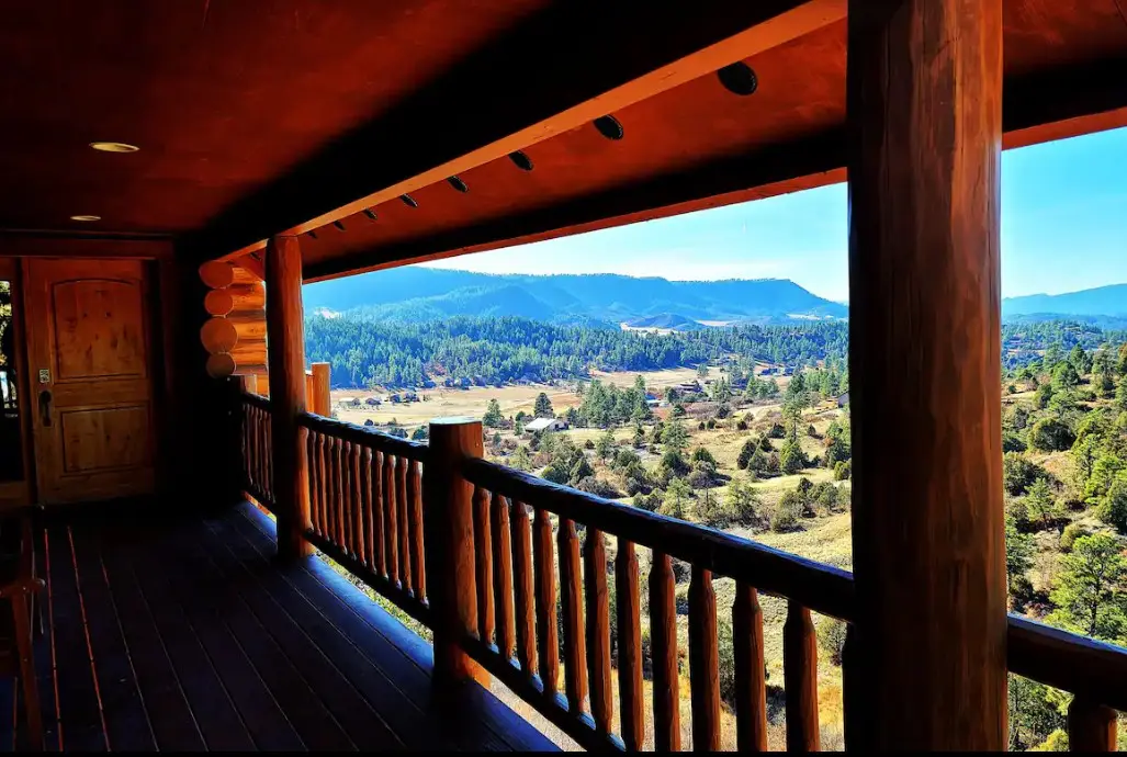 A view of the mountains from the porch of a log cabin.