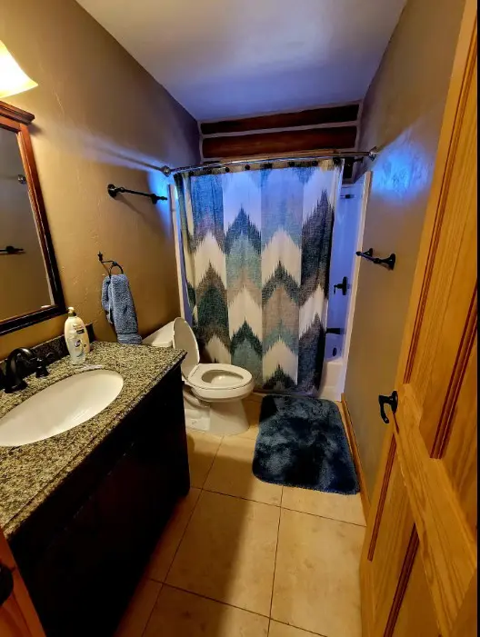 A bathroom with a blue shower curtain.