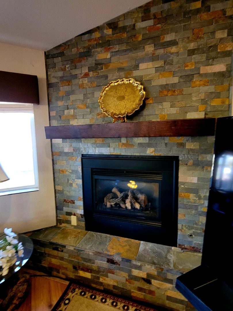 A living room with a stone fireplace and tv.