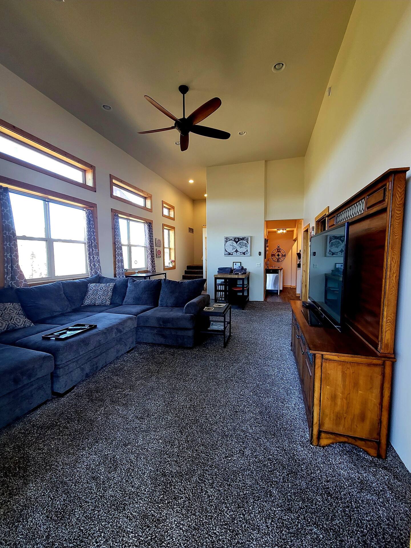 A living room with a flat screen tv and a ceiling fan.