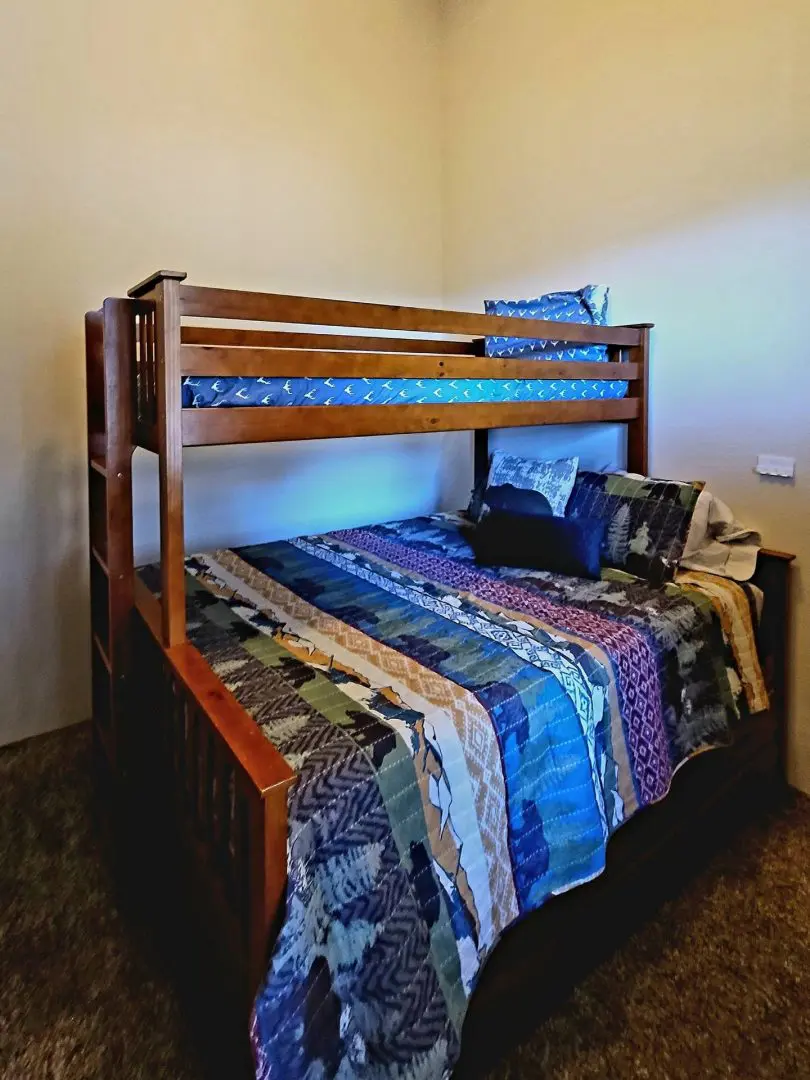 A bunk bed in a bedroom with a blue comforter.