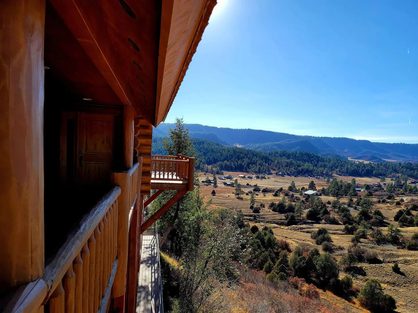 A view from the balcony of a log cabin overlooking a valley.