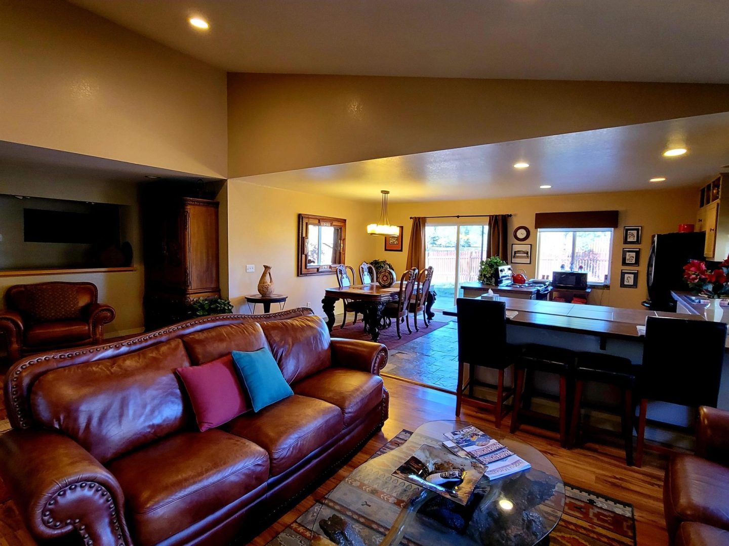 A living room with leather furniture and a kitchen.