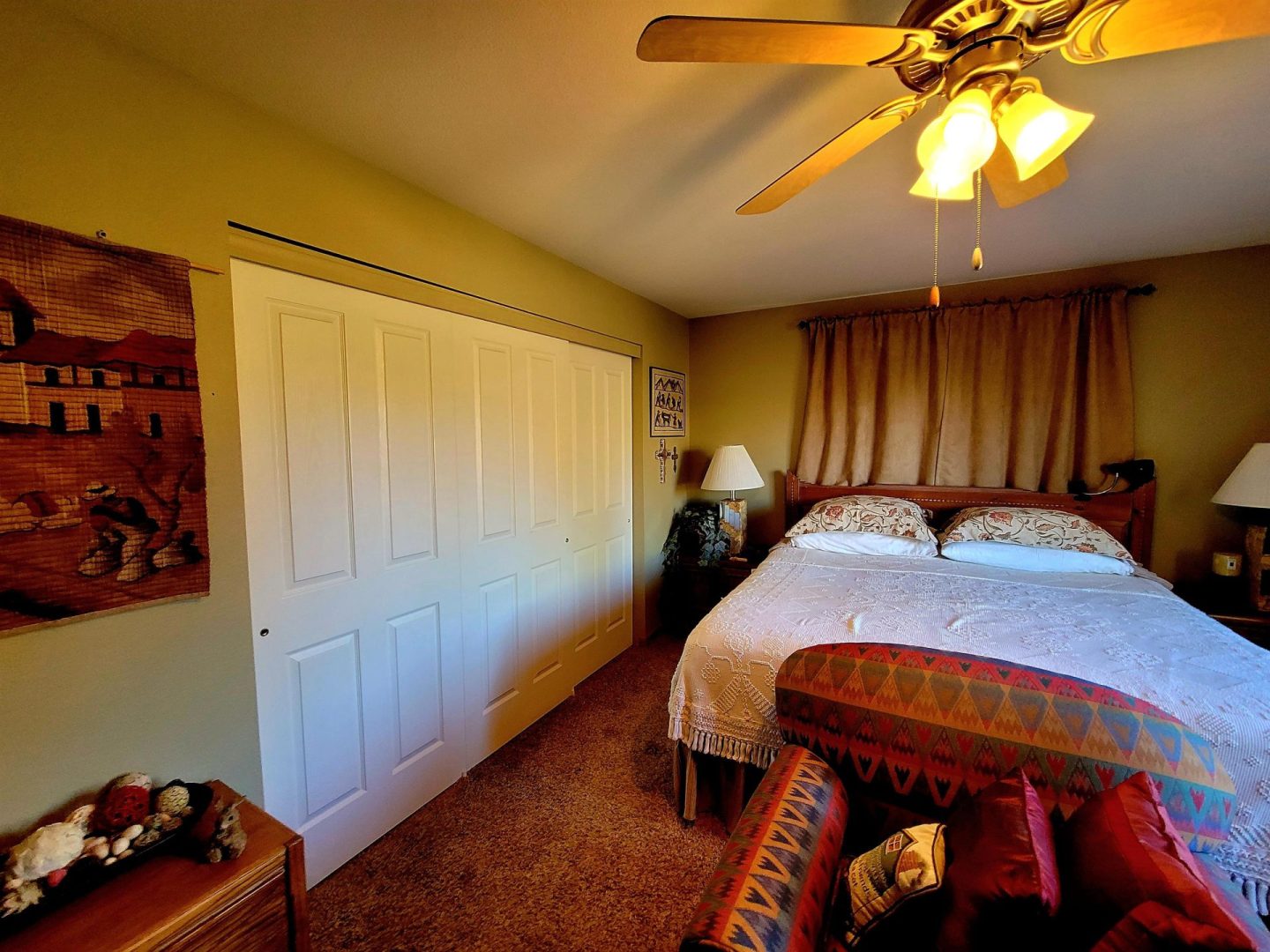 A bedroom with a ceiling fan and a bed.