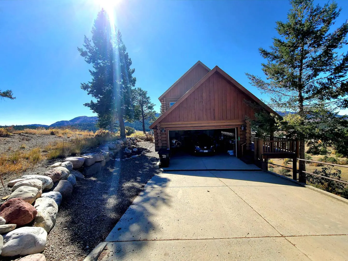 A house with a driveway leading to a cabin in the mountains.