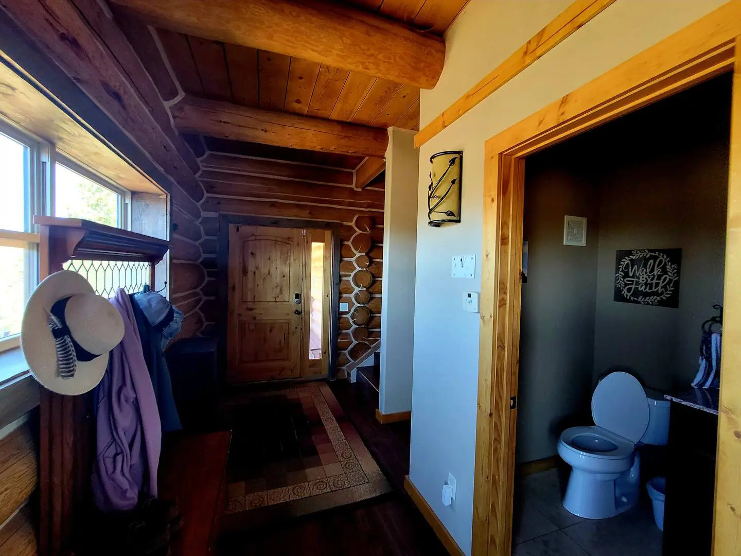 A bathroom in a log cabin with a toilet and hat.