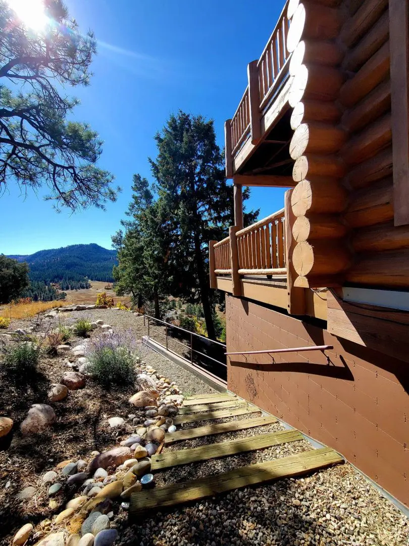 A view of a log cabin with rocks and trees.