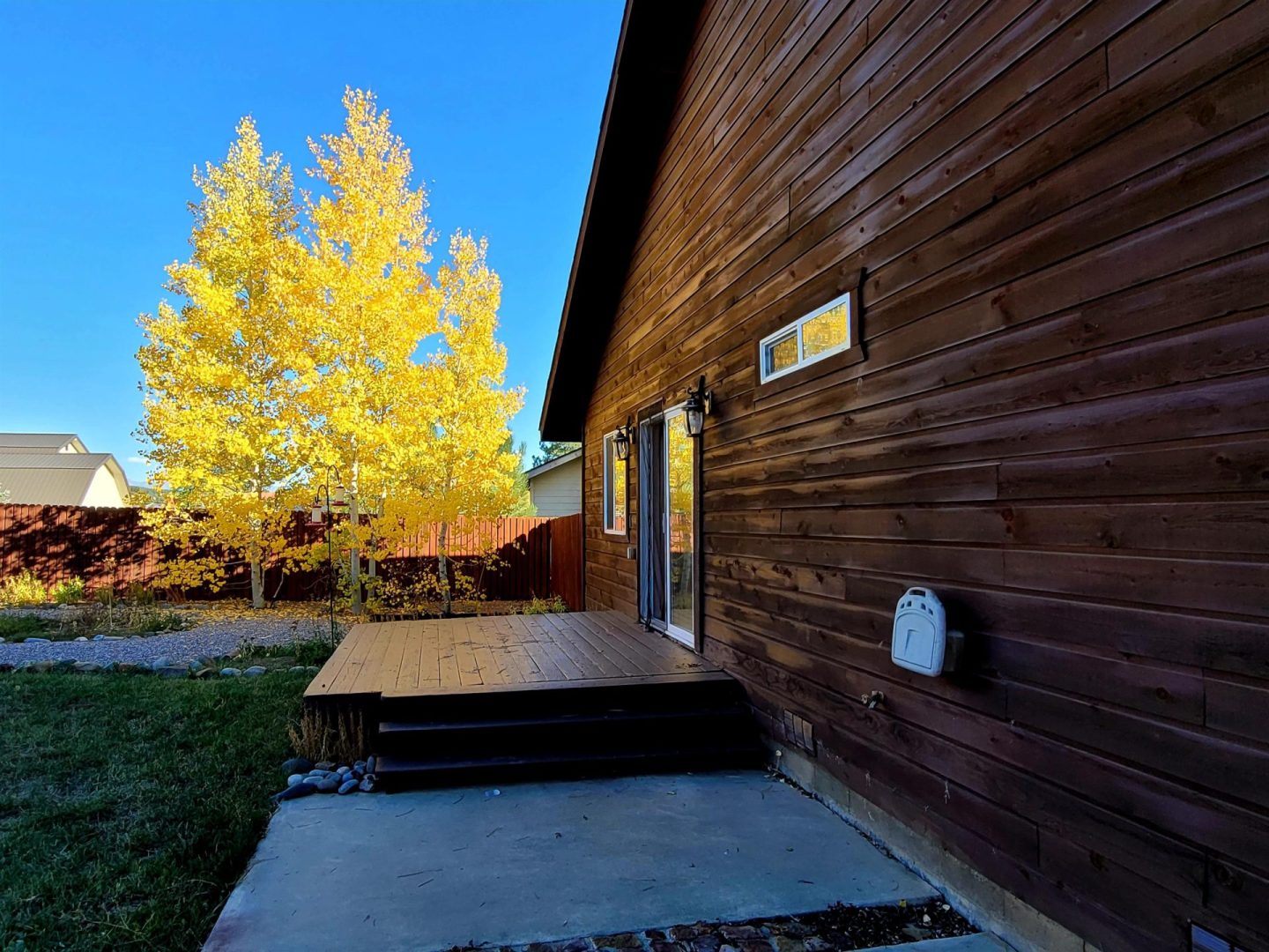 A house with a wooden deck and a yellow tree.