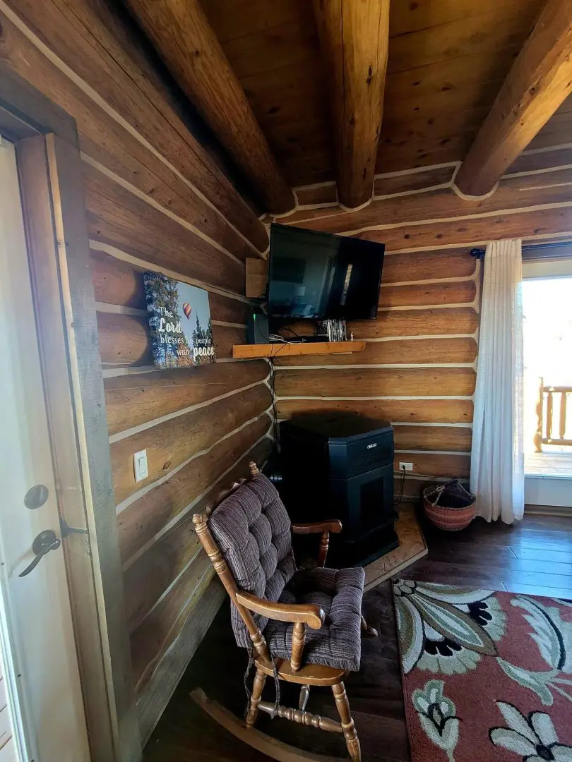 A log cabin with a rocking chair and tv.