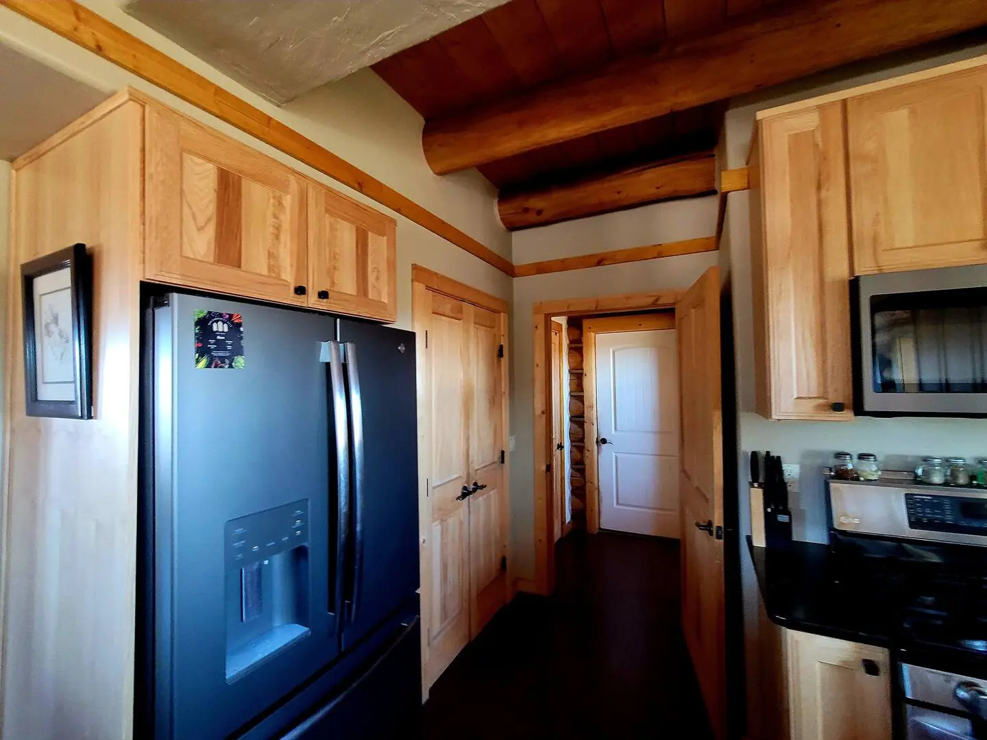 A kitchen with wood cabinets and a black refrigerator.