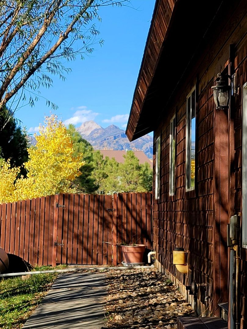 A house with a wooden fence and mountains in the background.