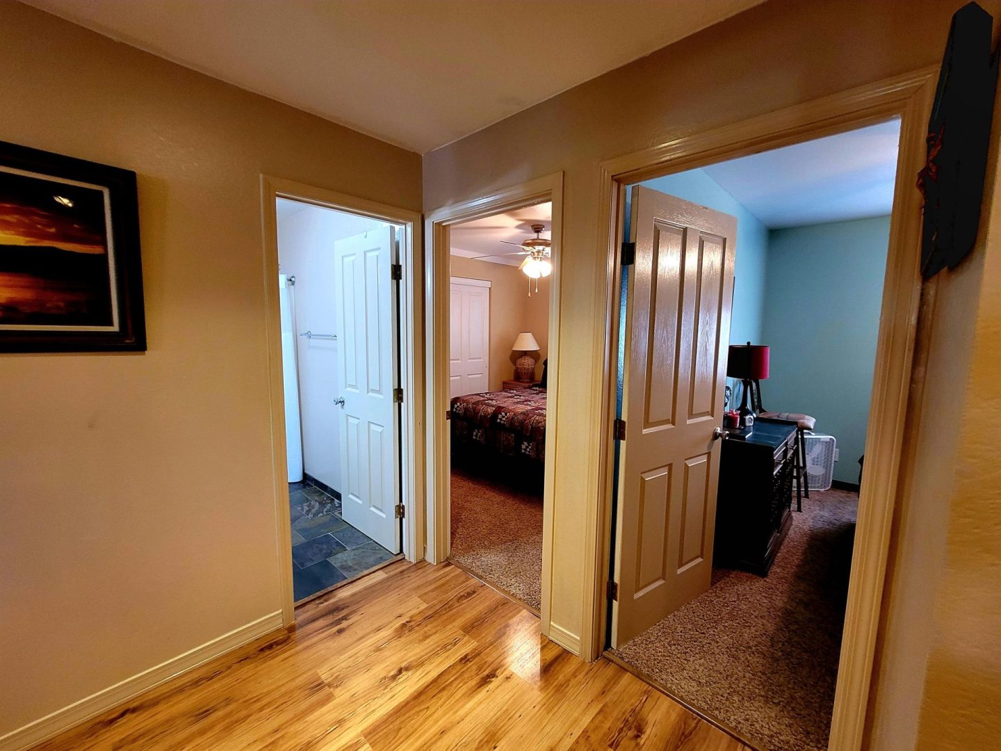 A bedroom with hardwood floors and a door leading to a bathroom.