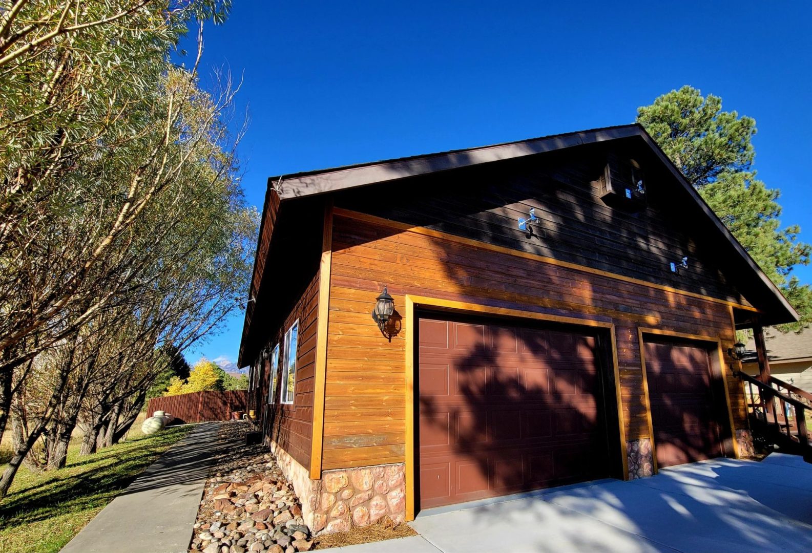 A house with two garages and a tree in the background.