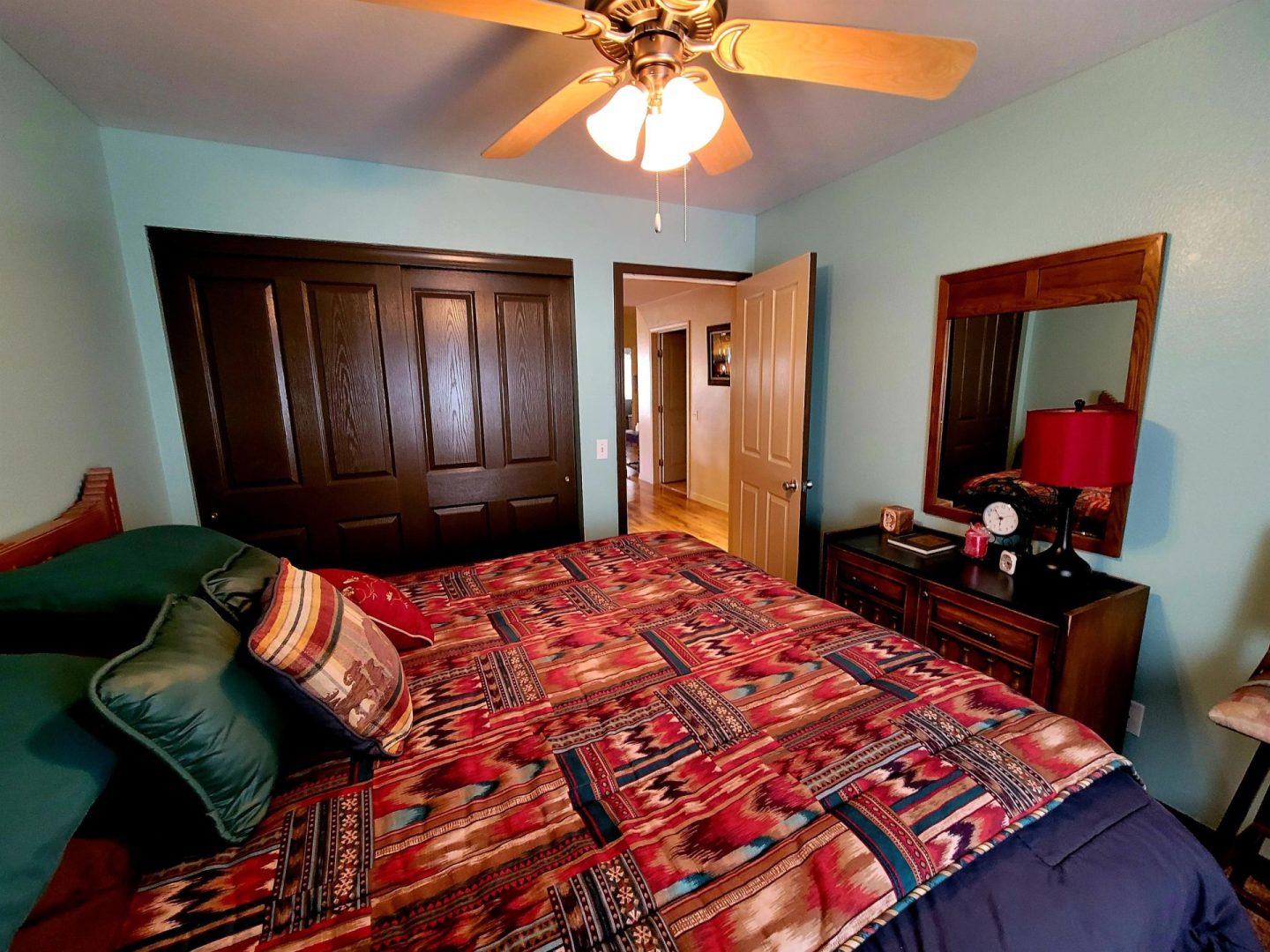 A bedroom with a bed, dresser, and ceiling fan.