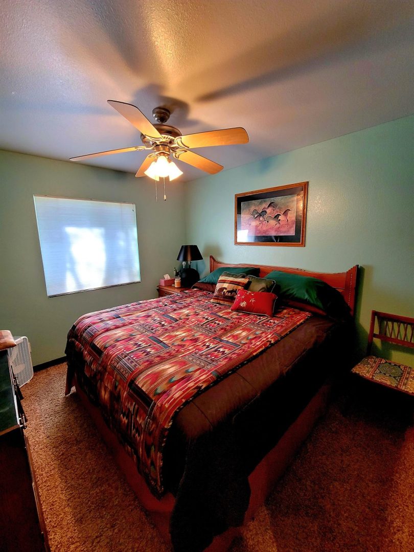 A bed in a bedroom with a ceiling fan.