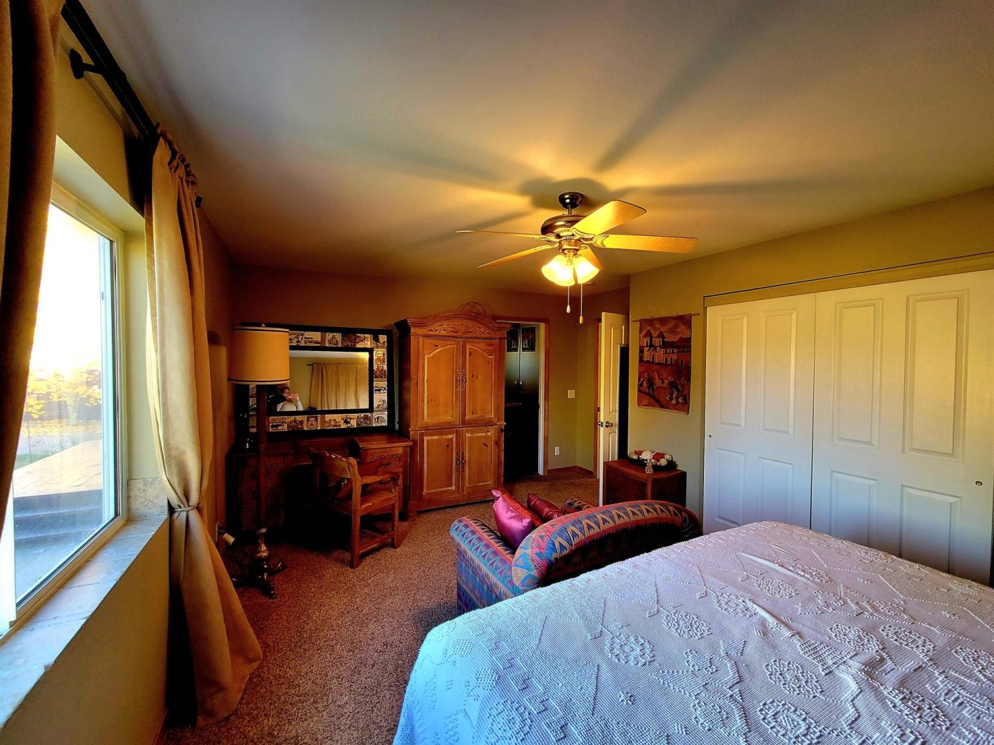 A bedroom with a ceiling fan and a bed.