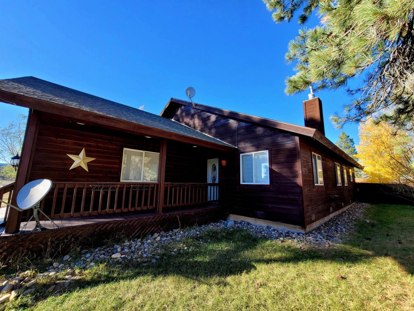 A cabin in the woods with a star on the front porch.