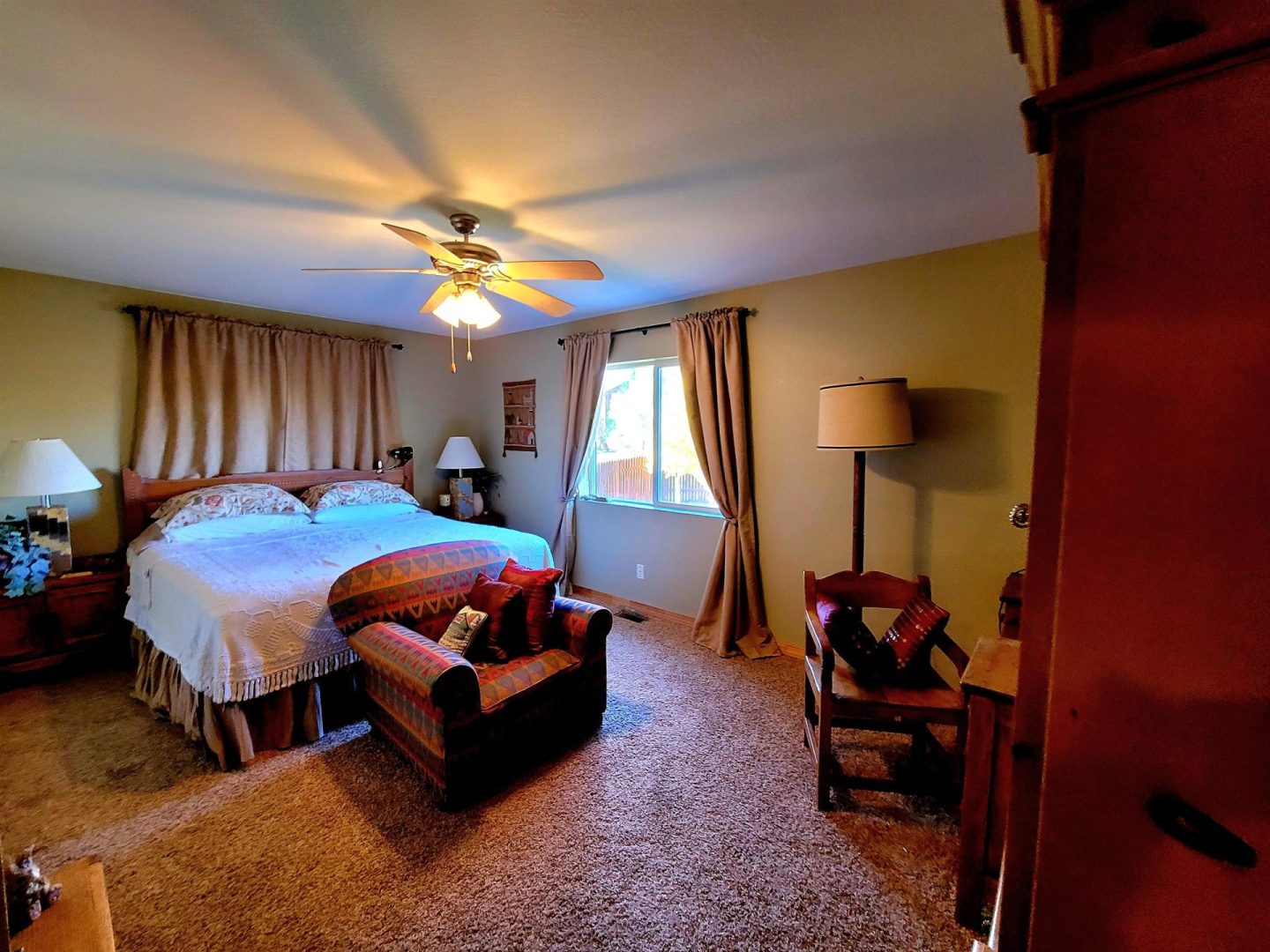 A bedroom with a bed, a chair, and a ceiling fan.